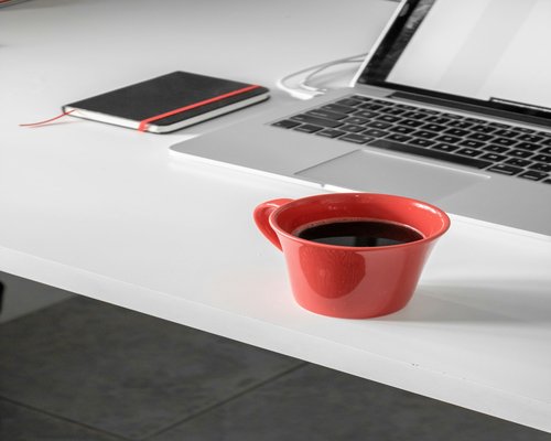 A clean desk with a coffee mug, empty chair implying a break